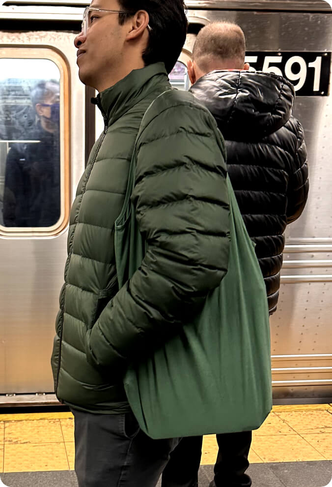 A man waiting for a subway train with an Always Tote.